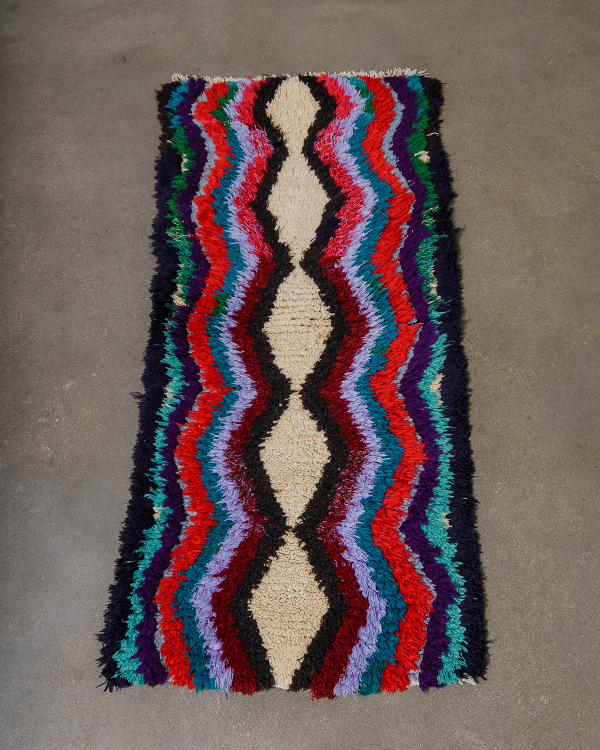 Multicolored woven rug with wavy pattern on a gray surface